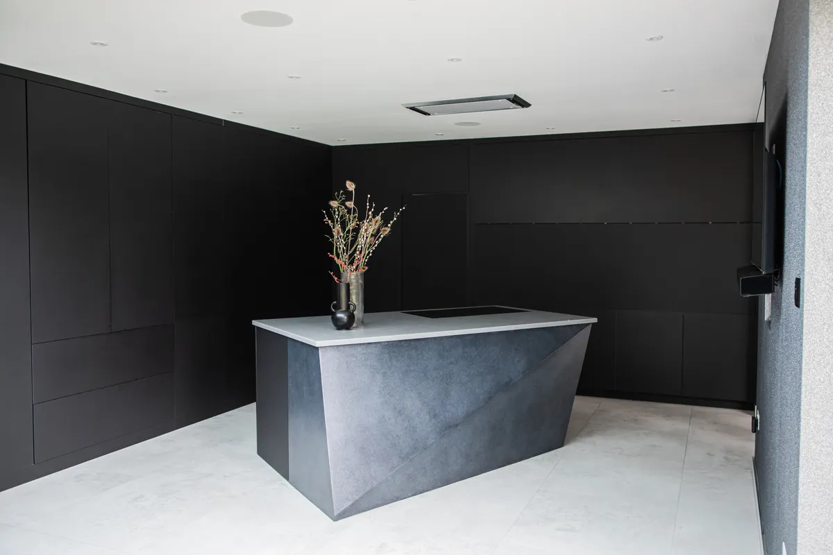 Black handleless kitchen around a faceted stone island