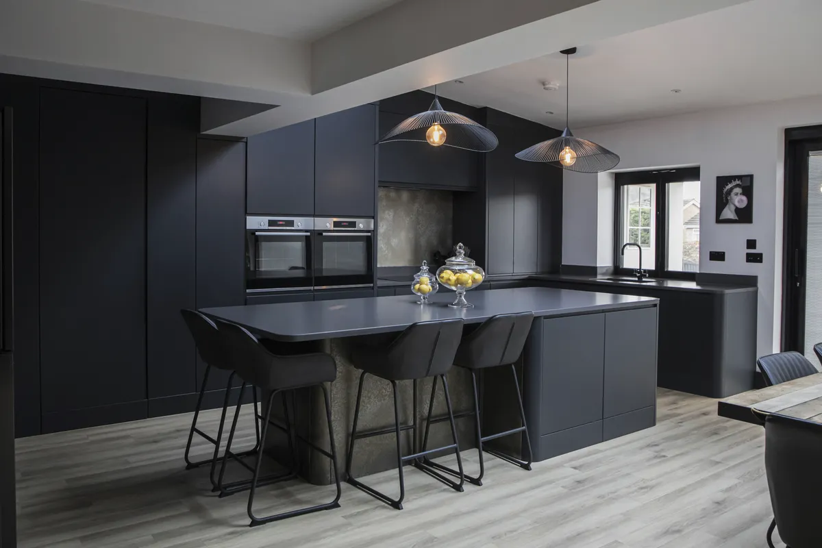Dark handleless kitchen with a bronze-finish island and bar stools