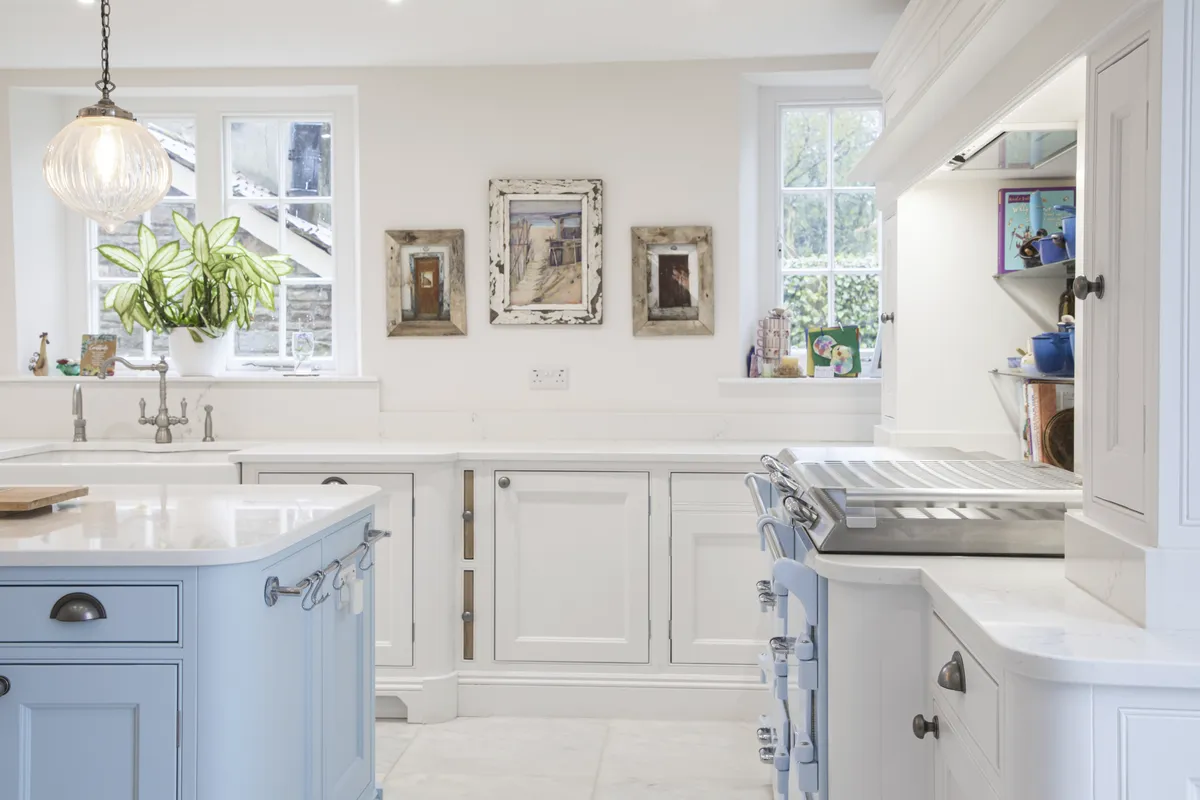 White painted kitchen with a pale blue island and a range cooker