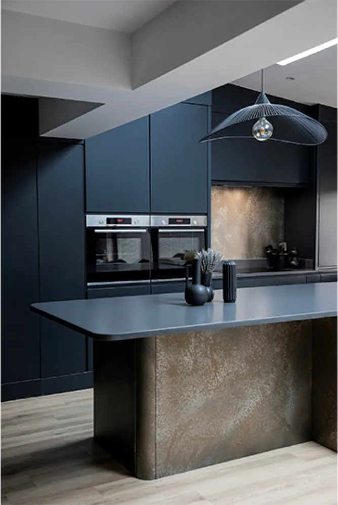 Dark blue handleless kitchen with a bronze-finish island and twin ovens