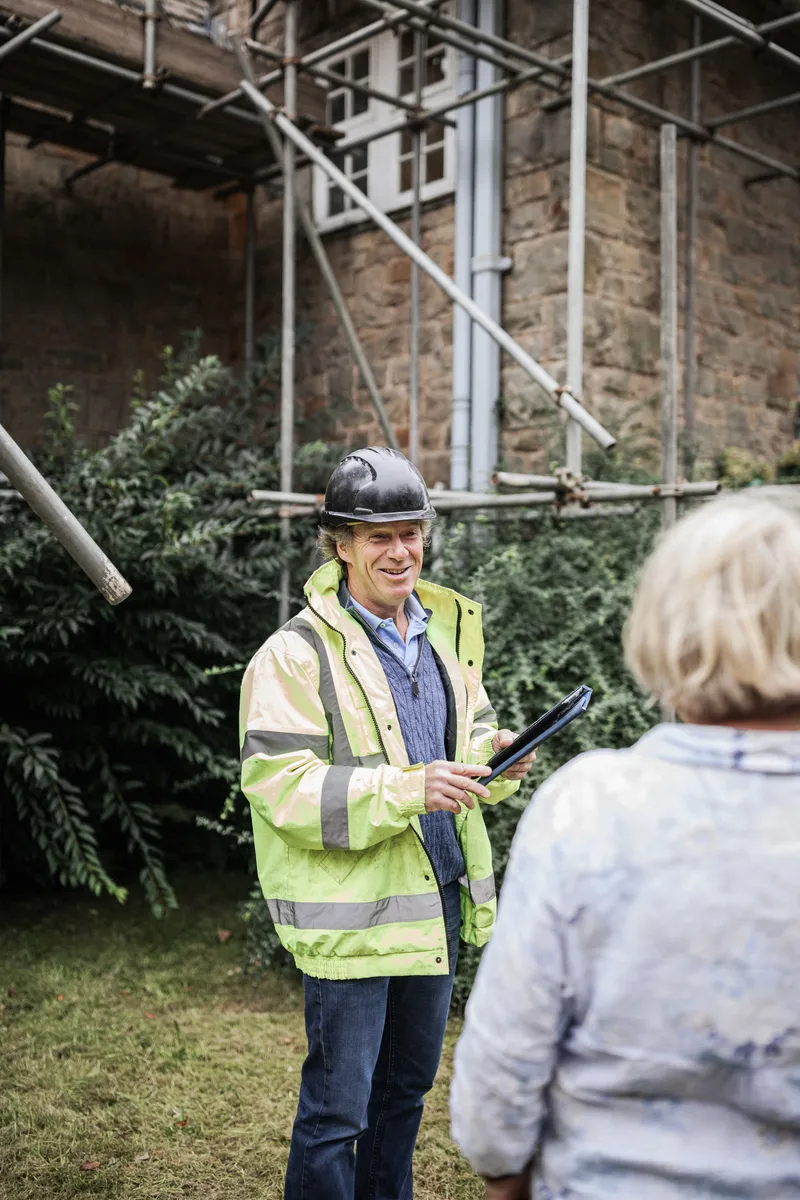 Our project manager in a hard hat talking a client through her build on site