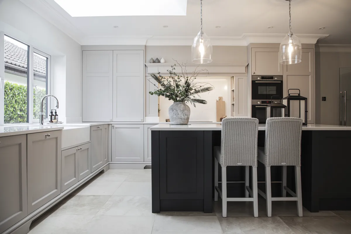 Cream shaker kitchen with a black island, wicker stools and glass pendant lights